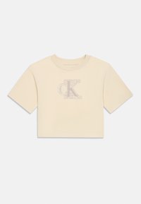 Κοντομάνικο cropped t-shirt σε ανοιχτό κρεμ ύφασμα με απαλή υφή, που διαθέτει ένα κεντημένο λογότυπο 'CK' σε διακριτικό σχέδιο.