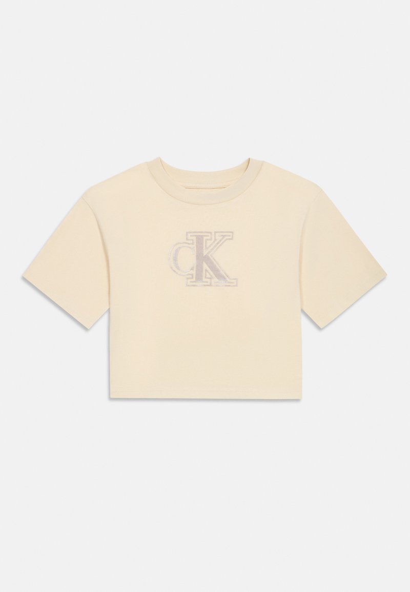 Κοντομάνικο cropped t-shirt σε ανοιχτό κρεμ ύφασμα με απαλή υφή, που διαθέτει ένα κεντημένο λογότυπο 'CK' σε διακριτικό σχέδιο.