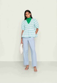 Top peplum risca turquoise clara com mangas bufantes, combinado com calças azul claro, bolsa off-white e sandálias com tiras. Texturas suaves.
