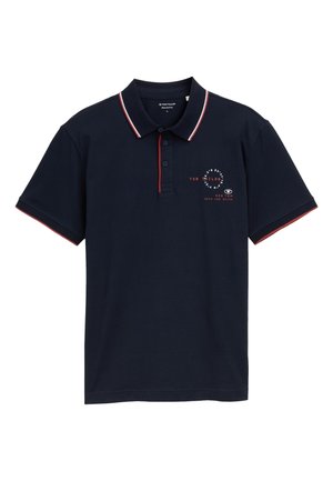 Navy blue polo shirt with red and white accents, three-button placket, and a front logo print. Made of cotton, featuring short sleeves.