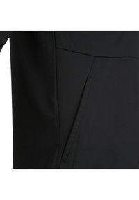 Zwart kledingstuk met een soepele, matte textuur en een diagonale zakdetail aan de voorkant. Het ontwerp is eenvoudig en gestroomlijnd.