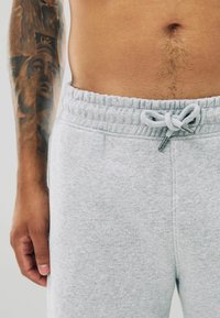 Lichtgrijze sweatpants met een elastische tailleband, verstelbaar trekkoord en zijzakken. Zachte structuur, middelhoge pasvorm en casual ontwerp.