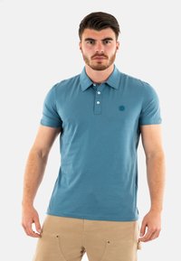 Polo a maniche corte da uomo in azzurro chiaro, realizzato in tessuto morbido. Presenta un colletto, una pattina con bottoni e un piccolo logo ricamato sul petto.