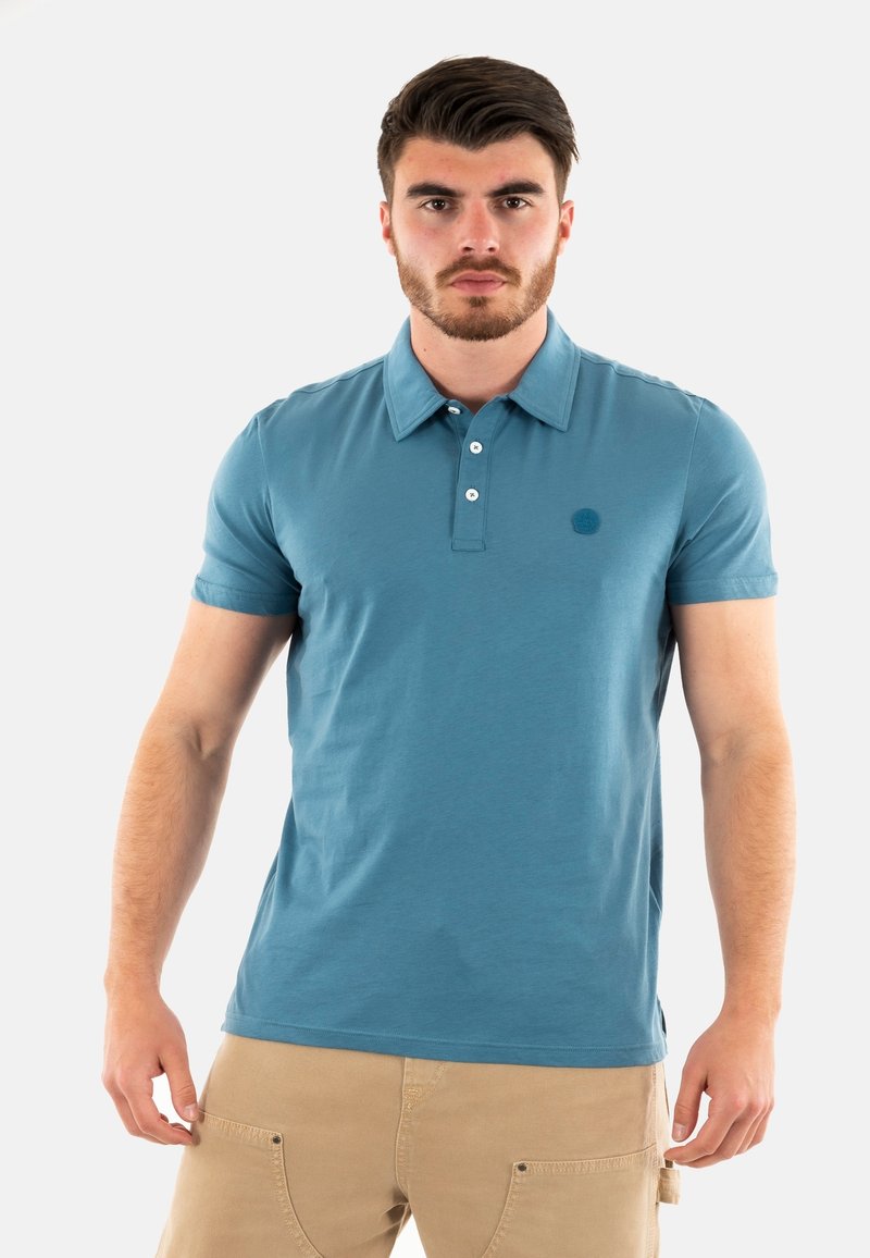 Polo a maniche corte da uomo in azzurro chiaro, realizzato in tessuto morbido. Presenta un colletto, una pattina con bottoni e un piccolo logo ricamato sul petto.