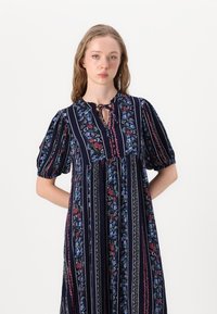 Navy floral print dress with puff sleeves, keyhole neckline, vertical stripes, and a loose silhouette, featuring colorful patterns throughout.