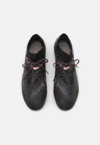Scarpe da ginnastica nere con una tomaia in maglia testurizzata, caratterizzate da accenti riflettenti e lacci scuri, progettate per prestazioni e supporto.