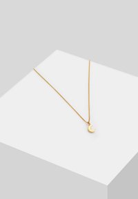 Collana con pendente color oro che presenta un ciondolo a forma di luna crescente su una delicata catena. La superficie liscia e il design minimalista mettono in risalto l'eleganza.