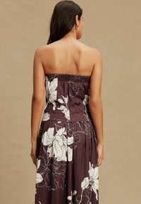 Rochie fără bretele în burgund adânc, cu imprimeu mare floral alb. Material moale, cu fustă plisată și corset elastic pentru o potrivire confortabilă.