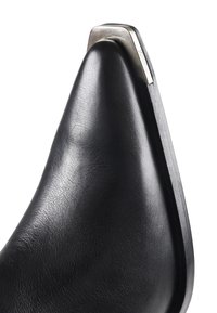Scarpa in pelle nera con punta appuntita, con un accento metallico sul tallone. Texture liscia e design elegante e minimalista.