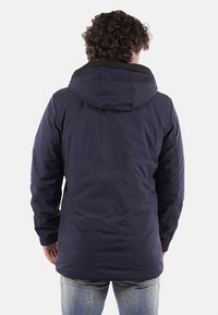 Giacca isolata blu navy con cappuccio, in tessuto strutturato e dal taglio lungo, dotata di tasche laterali e finitura liscia.