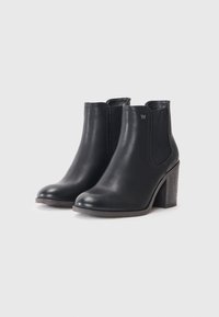 Botines de cuero negro hasta el tobillo con punta redondeada, paneles laterales elásticos y tacón apilado. Presenta un pequeño logotipo en el costado.