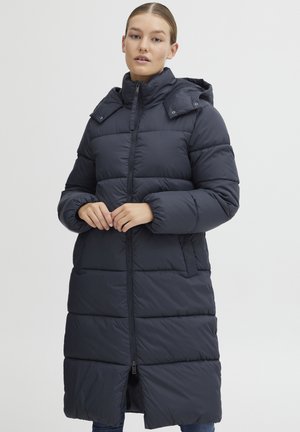 Manteau rembourré en marine foncé, avec une fermeture éclair à l'avant, une capuche amovible, une texture matelassée et des poches latérales. Mi-long, avec une coupe décontractée.