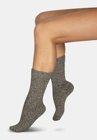Graue, strukturierte Knöchelsocken mit einem gerippten Bündchen und einem weichen Material. Das Design legt Wert auf Komfort und Wärme.