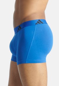 Modré sportovní boxerky s černým elastickým páskem s logem. Měkký materiál s přiléhavým střihem, který zvýrazňuje kontury a švy.