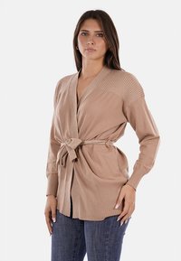 Cardigan lavorato a maglia beige con maniche a coste e cintura in vita, caratterizzato da un profondo scollo a V e una vestibilità morbida. Texture liscia e design leggero.