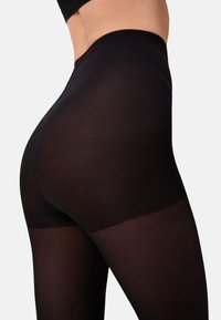 Zwarte leggings hebben een getextureerd, geribbeld ontwerp met een gladde bovenkant, wat zorgt voor een aangesloten silhouet in een mid-rise stijl.