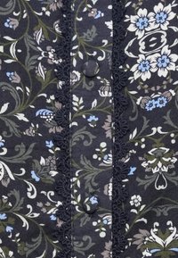 Dark fabric with intricate blue, white, and green floral patterns, featuring a central strip with covered buttons and decorative black lace trim.