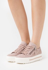 Rosa mockasneakers med vadderad krage, snörning fram och en sidodragkedja. Vit platåsula med zigzagmönster.