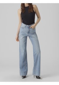 Bretta jeans i ljus denim med hög midja, kombinerade med en figurnära svart ribbad linne. Har sömnadsdetaljer och framt fickor.