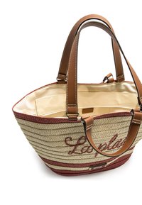 Bolso de paja trenzada con asas de cuero marrón. Presenta acentos rojos y bordado de "La playa" en el exterior. Interior espacioso.