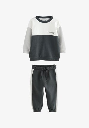 Dwuczęściowy zestaw dla malucha z bluzą z białymi, szarymi i ciemnoszarymi blokami kolorystycznymi oraz dopasowanymi spodniami dresowymi z bocznymi paskami i elastycznym pasem.