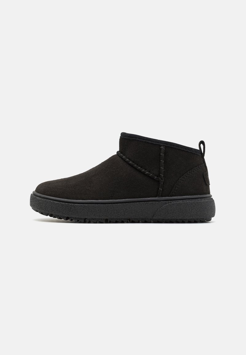 Botines de ante negro con suela de goma texturizada, que presentan acentos cosidos y una lengüeta en la parte posterior para facilitar su uso.