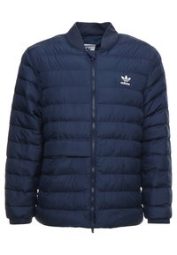 Marinblå puffjacka med horisontell quiltad mönster, full dragkedja och ribbad krage. Har en liten vit logga på bröstet.