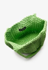 Green, woven crochet basket with a textured finish, featuring two handles and a small black label inside.