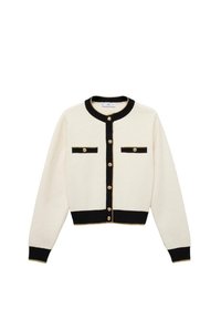 Cardigan blanc avec des accents noirs, fermetures à boutons dorés, deux poches thoraciques et des poignets et un ourlet côtelés. Texture douce, design classique.