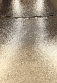 Tessuto in oro metallico con una texture liscia e riflettente. Presenta una leggera lucentezza, con un morbido gradiente da tonalità più scure a tonalità più chiare.