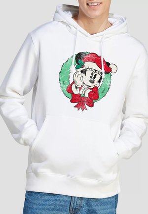 Person wearing white hoodie featuring vintage-style Minnie Mouse in Santa hat inside green Christmas wreath with red bow.