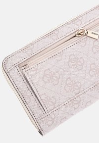 Ljusrosa plånbok gjord av texturerat material, med en dragkedjeficka och präglade blommönster. Guldfärgade detaljer.