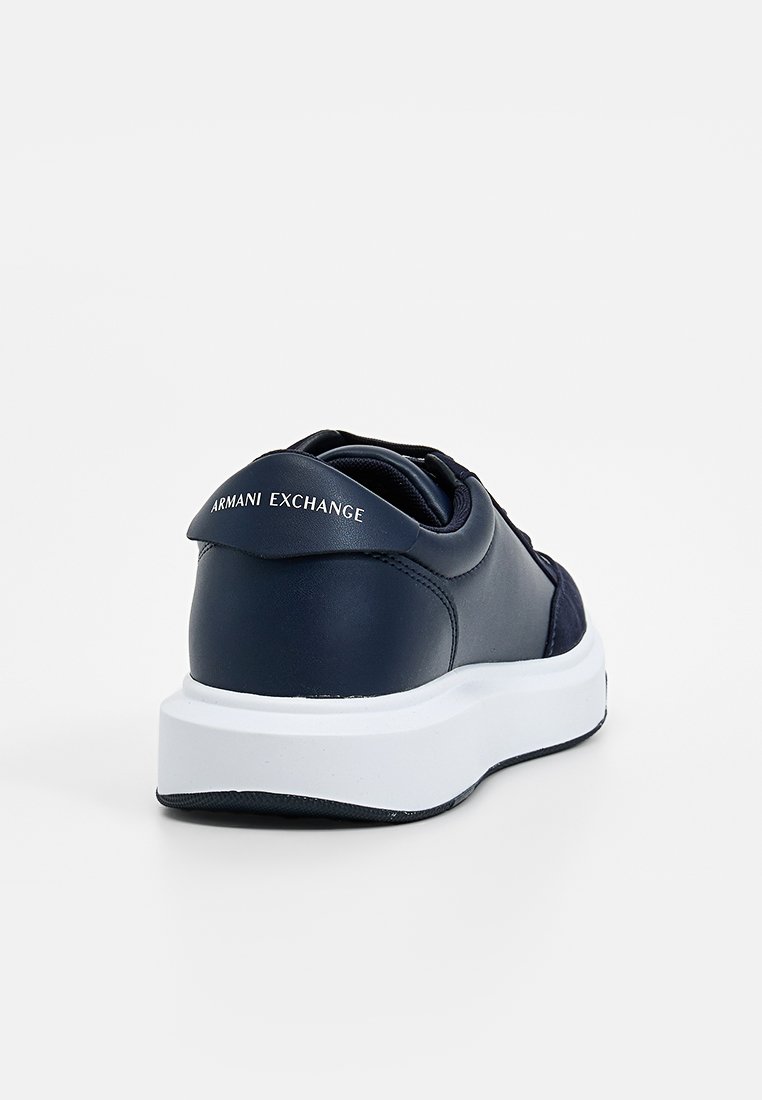 Sneaker in pelle blu navy con suola in gomma bianca, dotato di collo imbottito e logo impresso sul tallone. Design con punta arrotondata.