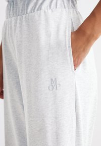 Ljusgrå sweatpants med elastisk midja, sidfickor och subtilt "MOP"-logotyp broderad med matchande tråd på benet.