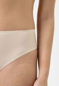 Beige Unterwäsche mit glatter Textur, niedrigem Schnitt und einfacher Taille; minimale Details und nahtlose Kanten.