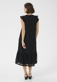 Rochie neagră din dantelă, cu tiv ondulat, mâneci scurte și un model floral intricate. Material ușor și siluetă lejeră pentru confort.