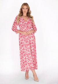 Maxikleid in zartem Rosa mit auffälligem roten Blumenmuster, V-Ausschnitt und drei Viertelärmel. Leichter Stoff mit einem fließenden Schnitt.