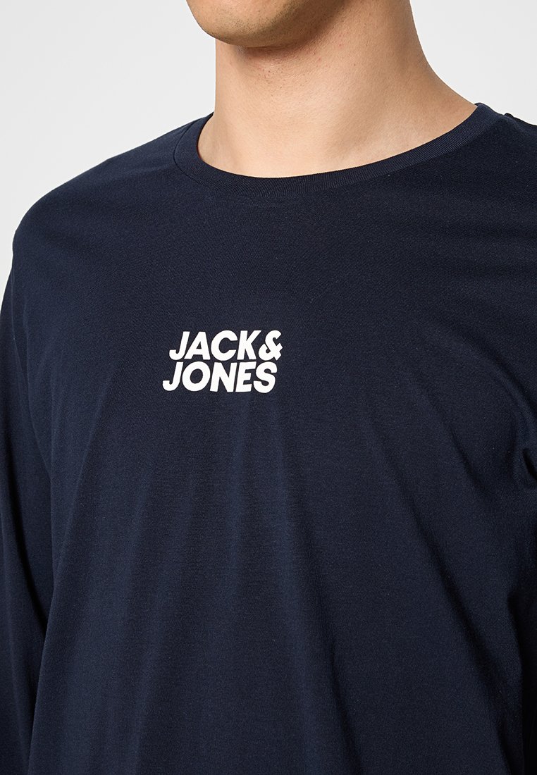 Granatowa koszulka z długim rękawem wykonana z bawełnianego materiału, z białym logo "JACK & JONES" na piersi, okrągłym dekoltem i miękką teksturą.