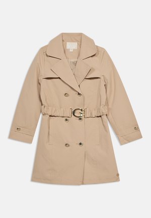 Beżowy dwurzędowy trencz z szerokimi klapami, złotymi guzikami oraz marszczonym paskiem z złotą klamrą w kształcie litery "G", ułożony na płasko na białym tle.