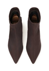 Botas tobilleras de tela marrón con puntera afilada y lados elásticos. Textura suave, mínimo detalle de costura en la parte superior, diseño moderno.