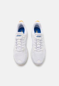 Vita sportskor med övre i nätmaterial, rund tå, snörning, blå innersula och subtilt gult inslag på hälen.