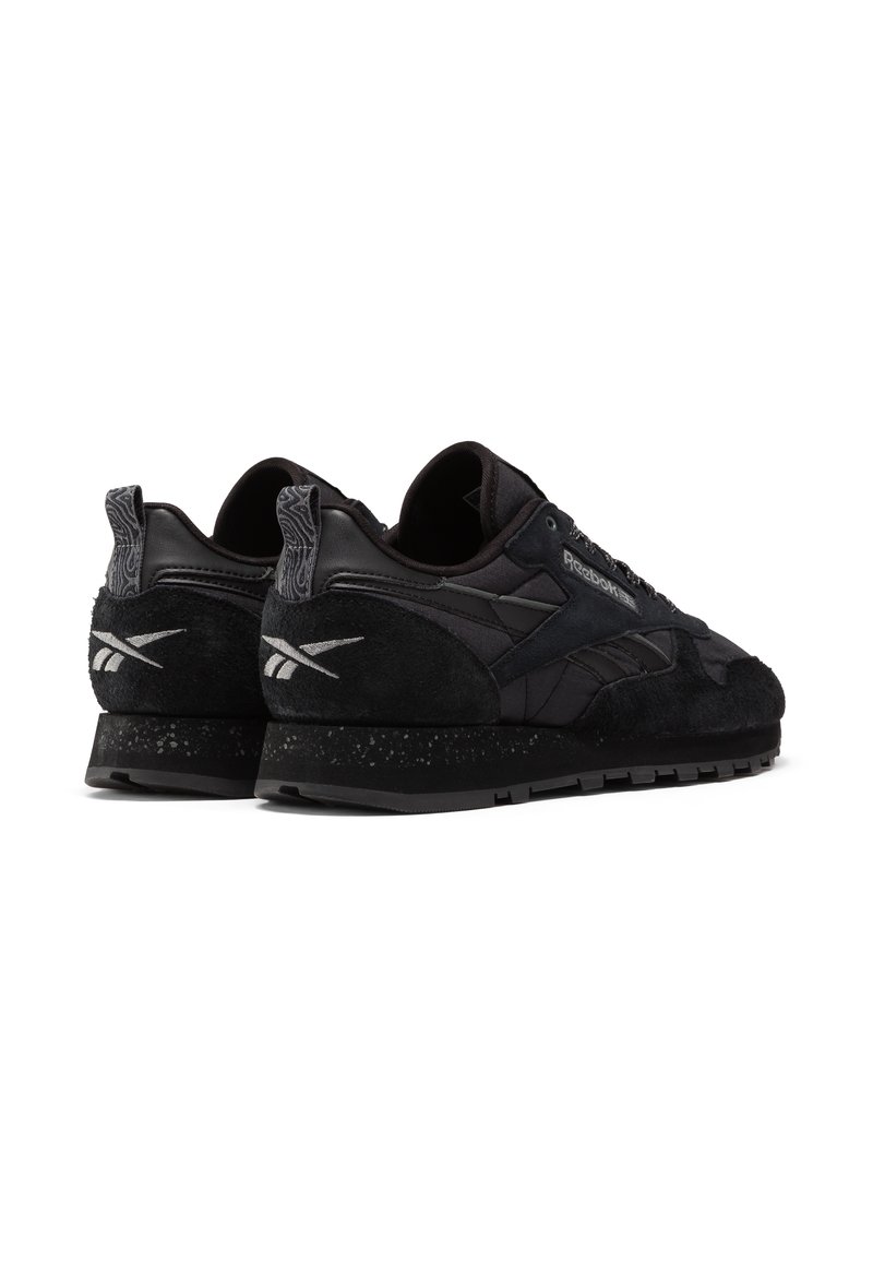 Czarne sportowe sneakersy z cholewą wykonaną z zamszu i skóry, z teksturowanymi akcentami oraz plamkowaną czarną podeszwą. Posiadają logo na pięcie.