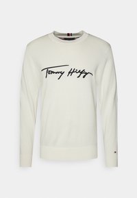 Cremefarbener Pullover mit schwarzem "Tommy Hilfiger"-Logo, rundem Ausschnitt, langen Ärmeln, gerippten Bündchen und Saum, gefertigt aus einem weichen Strickstoff.