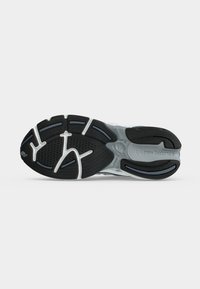 Μαύρη και γκρι σόλα παπουτσιού τρεξίματος New Balance με υφή πέλματος και λευκές γραμμές έμφασης σε απλό λευκό φόντο.