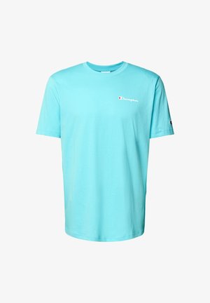 T-shirt en coton bleu clair avec des manches courtes, col rond, et un petit logo rouge et blanc sur la poitrine gauche. Design minimaliste.