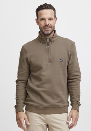 Brun zip-up sweatshirt med høj krave, der har et lille logo på brystet, ribbede ærmekanter og søm, lavet af blødt, struktureret stof.