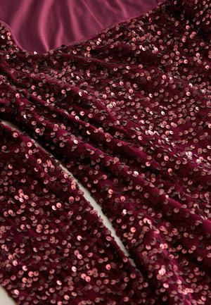 Tela de lentejuelas burdeos que cae con un acabado suave y texturizado. Lentejuelas redondas y brillantes crean un efecto de capas sobre un fondo de satén liso.