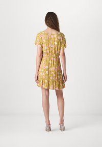 Robe fleurie avec un fond moutarde, manches courtes, taille élastique et ourlet volanté. Présente des motifs de fleurs roses et blanches.