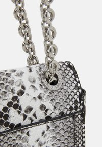 Borsa a tracolla con stampa serpente in bianco e nero, superficie testurizzata, dotata di una tracolla in catena argentata e un dettaglio logo circolare sul lato.