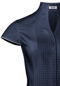 Navyblauw shirt met korte mouwen, met een V-hals, een textuurpatroon van kleine witte stippen en een knoopsluiting aan de voorkant.